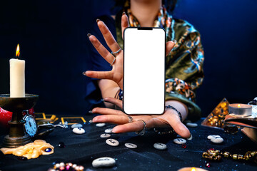 Sticker - Astrology. Witch's hands hold a cellphone with a white screen. Mock up. The concept of divination and predictions with the help of modern technologies