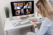 © shunevich - Back view of elegant female employee making notes while online conference. Successful business woman is sitting at the desk, using computer, remotely working on new project with colleagues