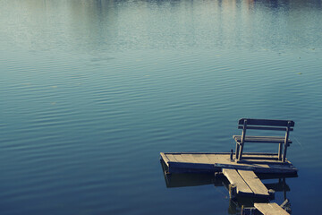 wooden scaffold pier with empty bench on a lake. calm peaceful place for fishing, recreation and meditation. High quality wallpaper photo