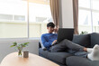 © snowing12 - young attractive asian man relaxing comfortably working on laptop in bright living room at his home.