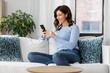 © Syda Productions - people, technology and leisure concept - happy young woman with wireless earphones and smartphone listening to music at home