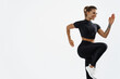 © Liubov Levytska - Determined athletic woman runner, fitness girl raising leg and doing cardio exercises, smiling on workout, wearing black activewear, sport clothing for training, white background