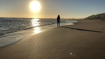 Poster - Silhouette of woman walking along coast