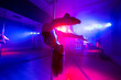 Pole dance. Young slender sexy woman dancing on a pole in the interior of a nightclub with light and smoke.