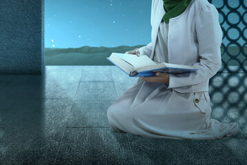 Wall Mural - Muslim woman in a veil sitting and reading the Quran