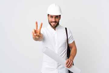 Canvas Print - Young architect man with helmet and holding blueprints isolated on white background smiling and showing victory sign