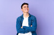 © luismolinero - Teenager caucasian  handsome man isolated on purple background looking up while smiling