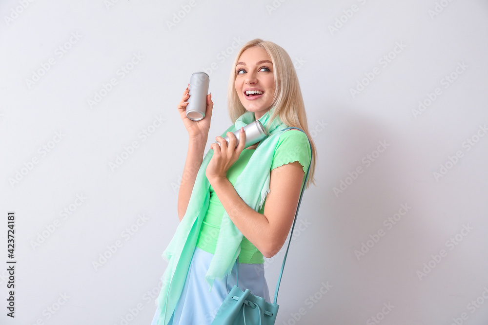 Beautiful young woman with soda on light background