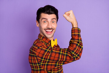 Poster - Photo of positive guy raise hand hold fist look camera wear bow tie checkered shirt isolated purple background