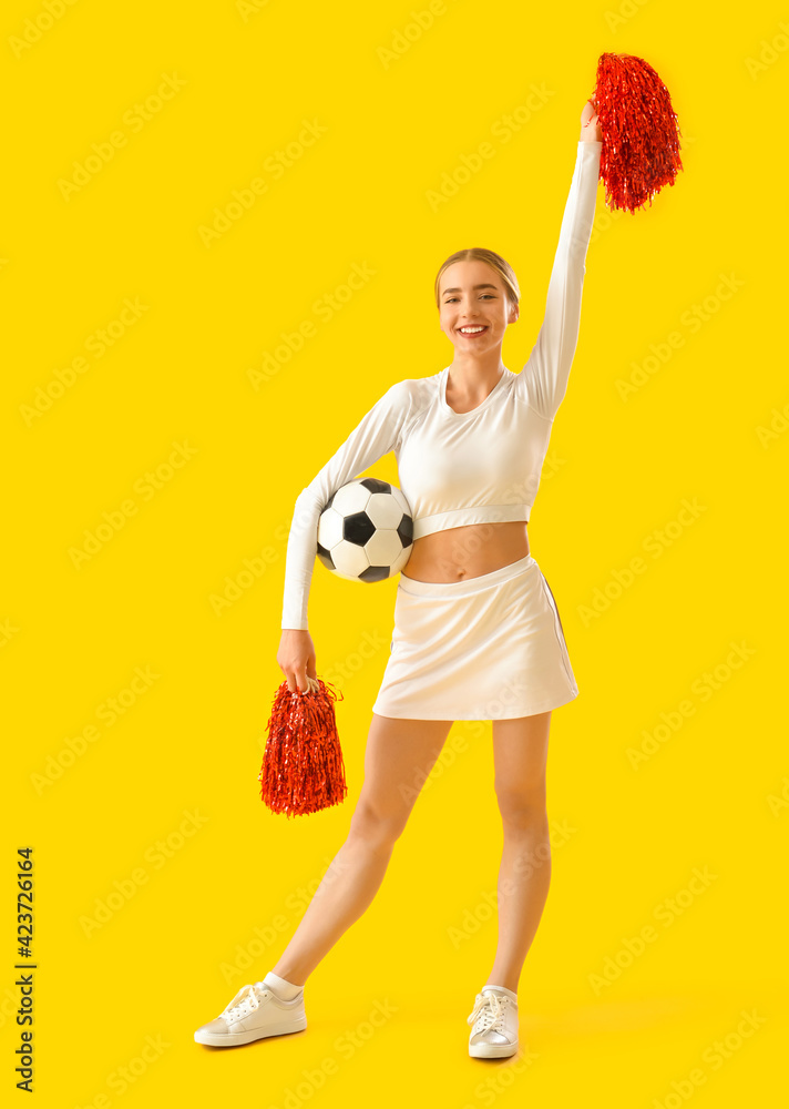 Beautiful cheerleader with soccer ball on color background