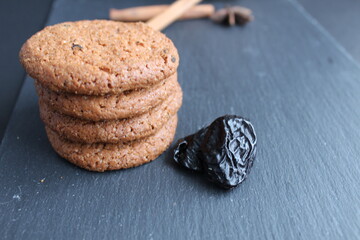 Canvas Print - Eating still life cookie oatmeal homemade with prunes and cinnamon sticks lies a stack of slides on a black background with room for text copyspace