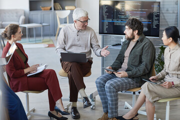 Wall Mural - High angle view at contemporary diverse business team sitting in circle during strategy meeting, focus on senior businessman in center