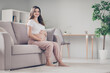 © deagreez - Full size profile side photo of happy woman sit sofa in living room touch baby belly inside home indoors
