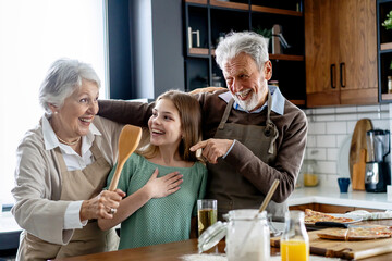 Wall Mural - Affectionate senior grandparents in love with child in kitchen