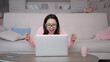 © GoSlow - Excited multi ethnic girl winner looks at laptop computer, screaming yes and celebrating mobile online game victory success or getting ecommerce shopping offer. Asian lady using app and celebrating
