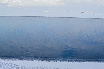 Winter horizontal blue river with sky reflection and frozen snowy banks. Minimalism. Natural north landscape. Top view