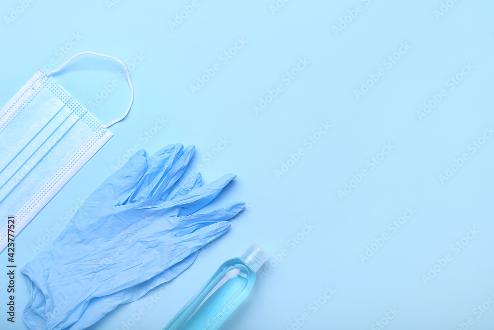 Medical mask, protective gloves and antiseptic on color background