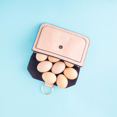 Wall Mural - Eggs in a small female purse. Minimal Easter concept on blue background