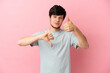 © luismolinero - Young Russian man isolated on pink background making good-bad sign. Undecided between yes or not