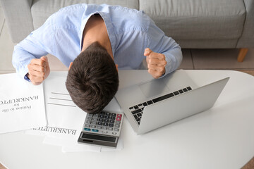 Poster - Stressed man with laptop and calculator at home. Bankruptcy concept