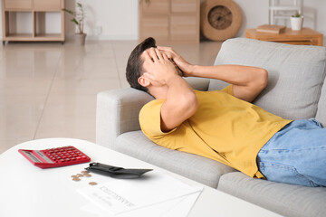 Poster - Stressed man lying on sofa at home. Bankruptcy concept