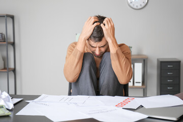 Wall Mural - Stressed man at table in office. Bankruptcy concept