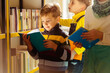 © Iryna - Child in school library. Kids read books. Little boy with his friends reading and studying. Three children at bookstore. Smart intelligent preschool kid choosing books.