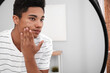 © Pixel-Shot - African-American teenage boy with acne problem at home