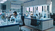 © Gorodenkoff - Team of Medical Research Scientists Conduct Experiments with Help of Microscope, Test Tubes, Micropipette and Writing Down Analysis Results on a Computer. Science Laboratory with Blurred Motion.