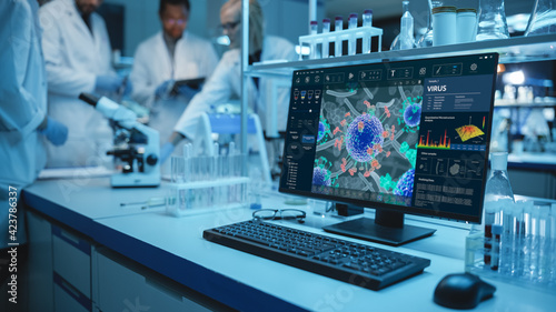 Shot of a Desktop Computer with Display Showing Virus Analysis Software User Interface. Diverse Team of Medical Research Scientists Have Meeting in Medical Research Laboratory in Background.