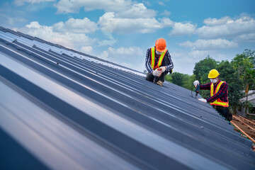 Two Roof concept of residential building under construction, Roofer worker safety wear using air or pneumatic nail gun and installing on new roof metal sheet.