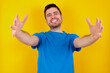 © Roquillo - young handsome caucasian man wearing blue t-shirt against yellow background looking at the camera smiling with open arms for hug. Cheerful expression embracing happiness.