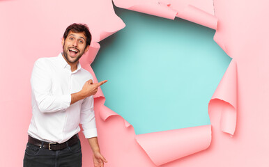 Wall Mural - young handsome indian man surprised expression against broken paper hole background