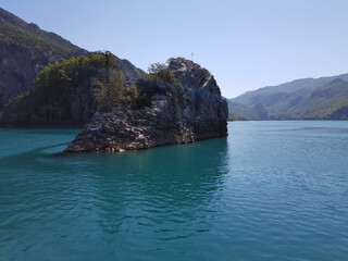 Seascape. Bay with green water against the background of mountains covered with forest on a cloudless sunny day.