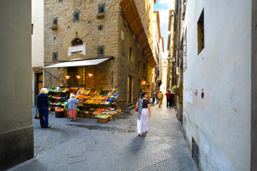 Wall Mural - Italians enjoying a narrow back alley with a fresh produce market near Piazza di Signoria in the Tuscan city of Florence, Italy.