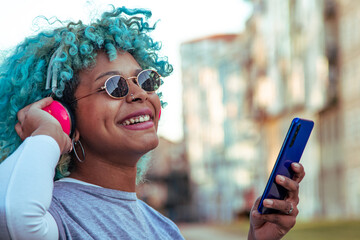 Wall Mural - afro american hipster girl listening to music with headphones in the city