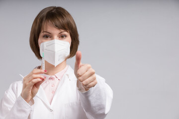 Wall Mural - female doctor or nurse with syringe pulled up with a vaccination serum shows thumbs up