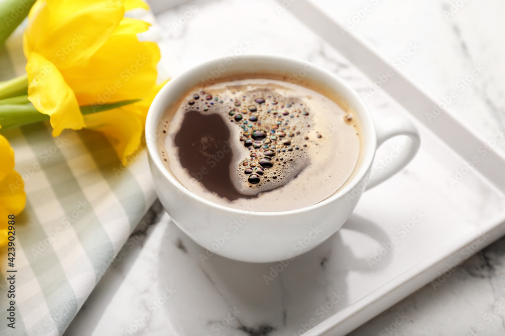 Cup of coffee with flowers on tray, closeup