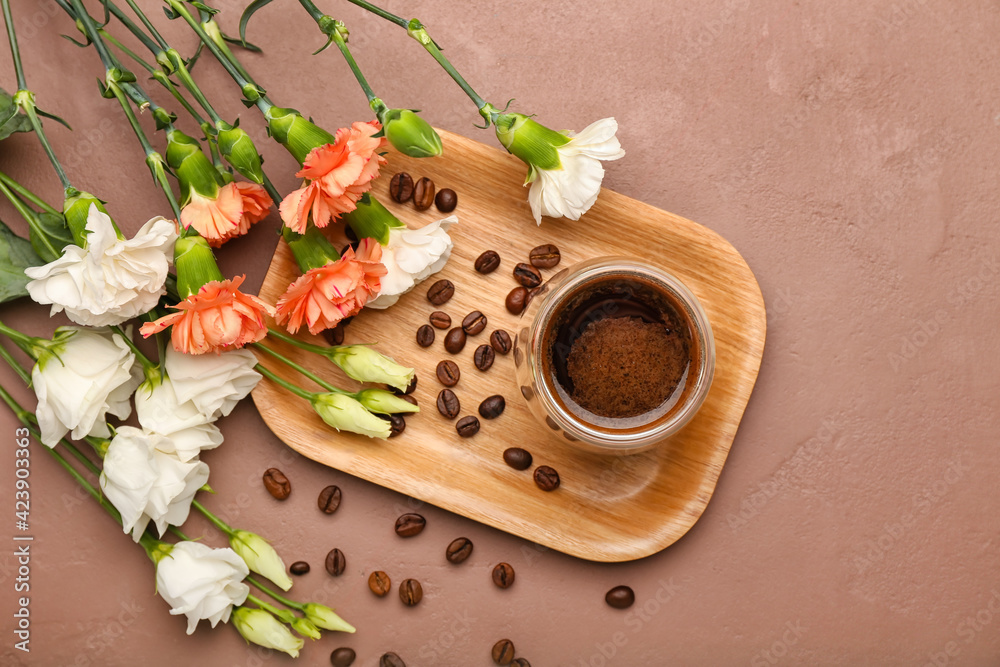 Cup of coffee with spring flowers on color background