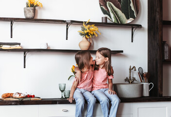 Two little girls sisters have fun together in the kitchen