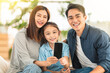 © Tom Wang - family with kid laughing and showing the smartphone on couch together