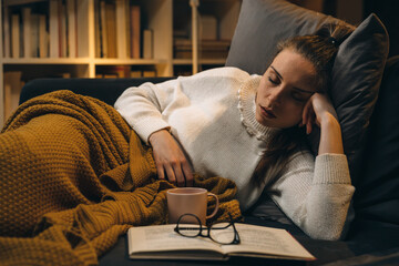 Wall Mural - woman fell asleep while reading book. she is relaxing on sofa at home