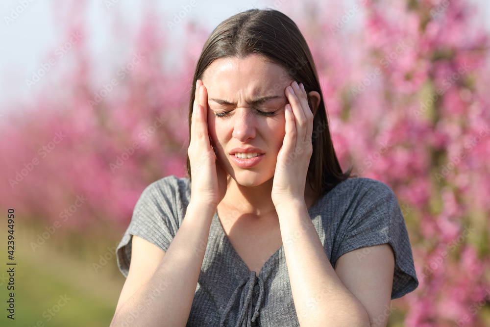 Woman suffering migraine in a flowered field - obrazy, fototapety, plakaty 