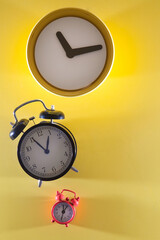 Three alarm clocks in different styles, sizes and colors. Yellow background