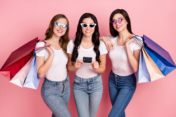 Poster - Photo of three young girls happy positive smile credit card shopping bags sale glasses isolated over pastel color background