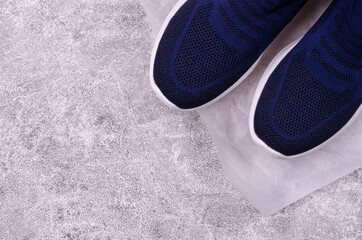 Knitted blue sneakers without laces on a gray background.