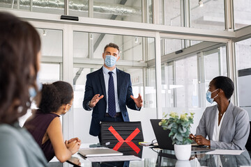 Wall Mural - Mature leader in meeting with his business team wearing face masks