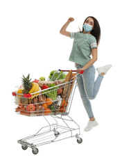 Sticker - Young woman in medical mask with shopping cart full of groceries on white background