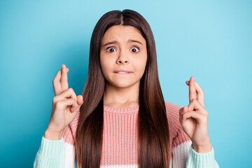 Photo of young preteen girl worried crossed fingers hope show fortune sign isolated over blue color background