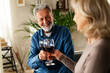 © JustLife - Senior woman and man drinking wine at home. Husband and wife celebrate the anniversary.